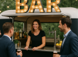 Een vrouw staat achter de bar en 2 mannen hebben een biertjevast